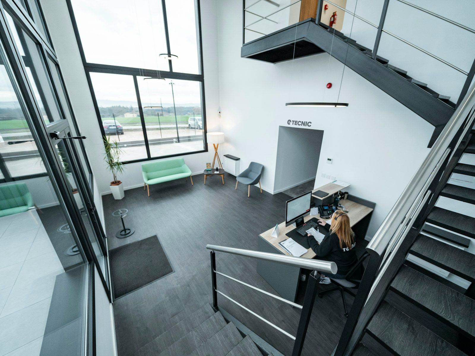 A receptionist at a modern clinic front desk with the Ops Hub on screen